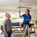 Ceiling fan repair guide showing an electrician inspecting a modern ceiling fan