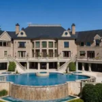 Luxury exterior view of Tyler Perry House featuring a grand modern mansion with the celebrity's face subtly blended into the lower-right landscaping for a premium architectural real estate presentation.